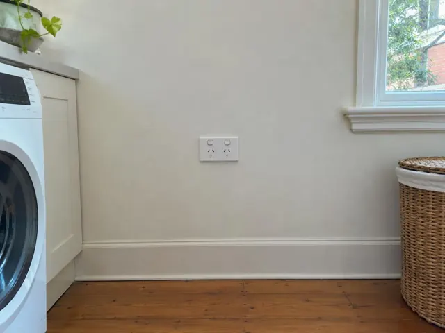 Double power point on a painted laundry wall beside a window and cabinet in Killara